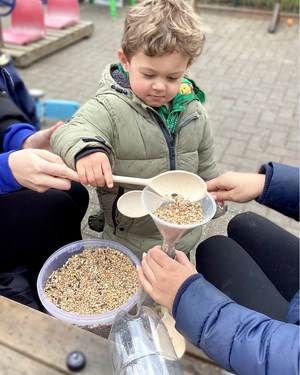 Children filling bottle with bird seeds