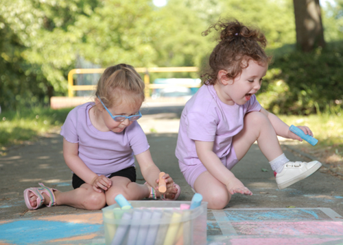 Two girls playing outside with chalk