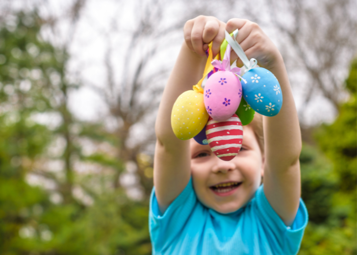 child holding up decorated eggs