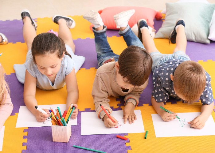 children drawing whilst lying on the floor 