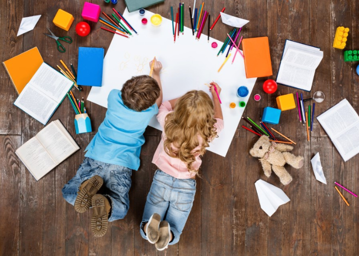 children drawing whilst lying on the floor 