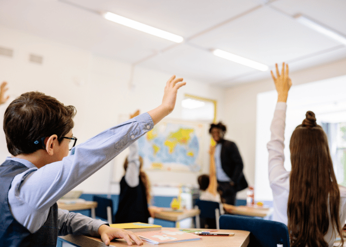 Students holding their hands up in a classroom