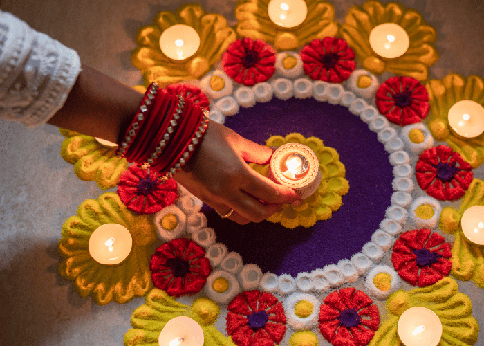 Hand placing tealight into the centre of a Rangoli