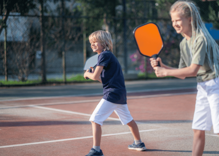 Two children playing pickleball on a court