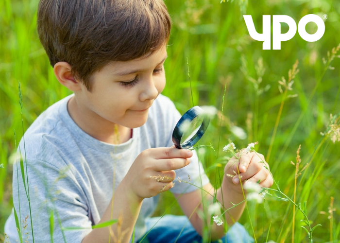 boy looking at plant with magnifying glass