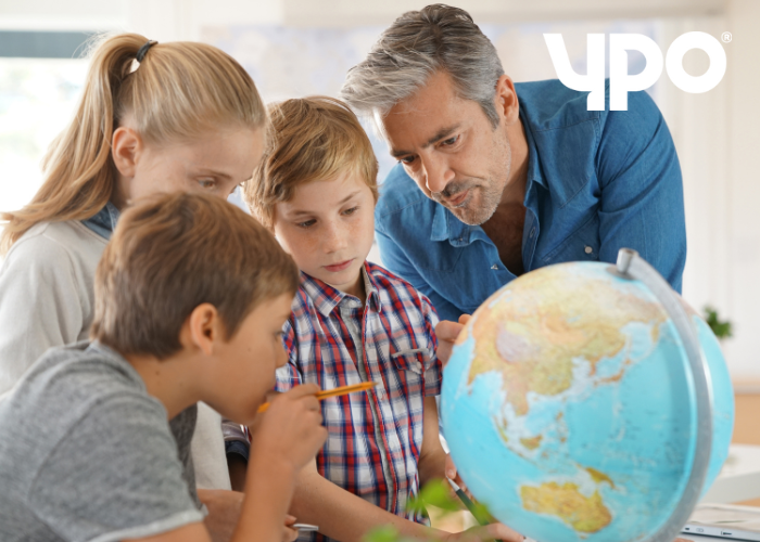 Three students and a teacher looking at a globe