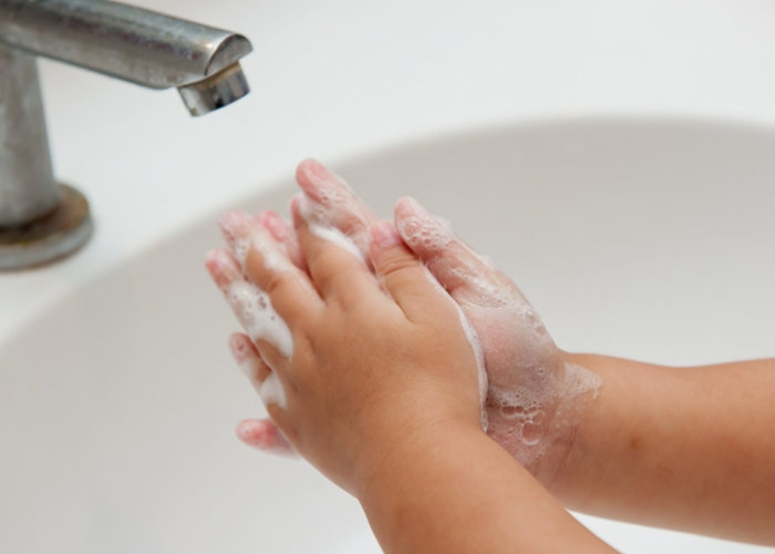 young child washing hands