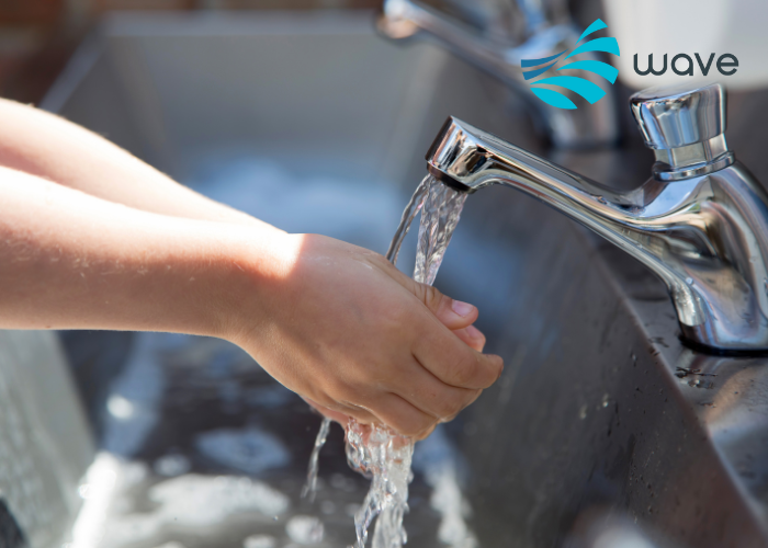 Child washing their hands under a running tap in a sink